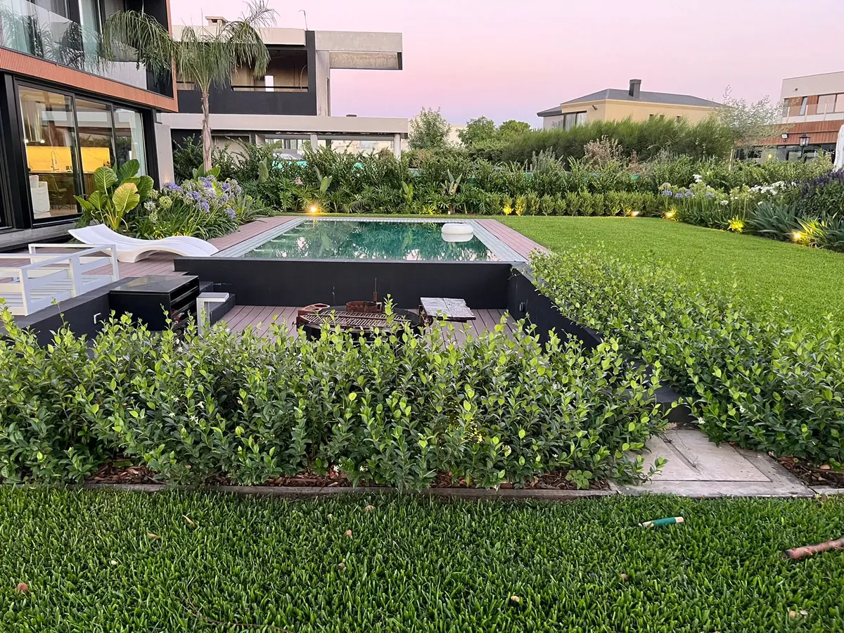 Jardim moderno com piscina, deck de madeira e vegetação exuberante — projeto CAN., por Baires Green, em Canning