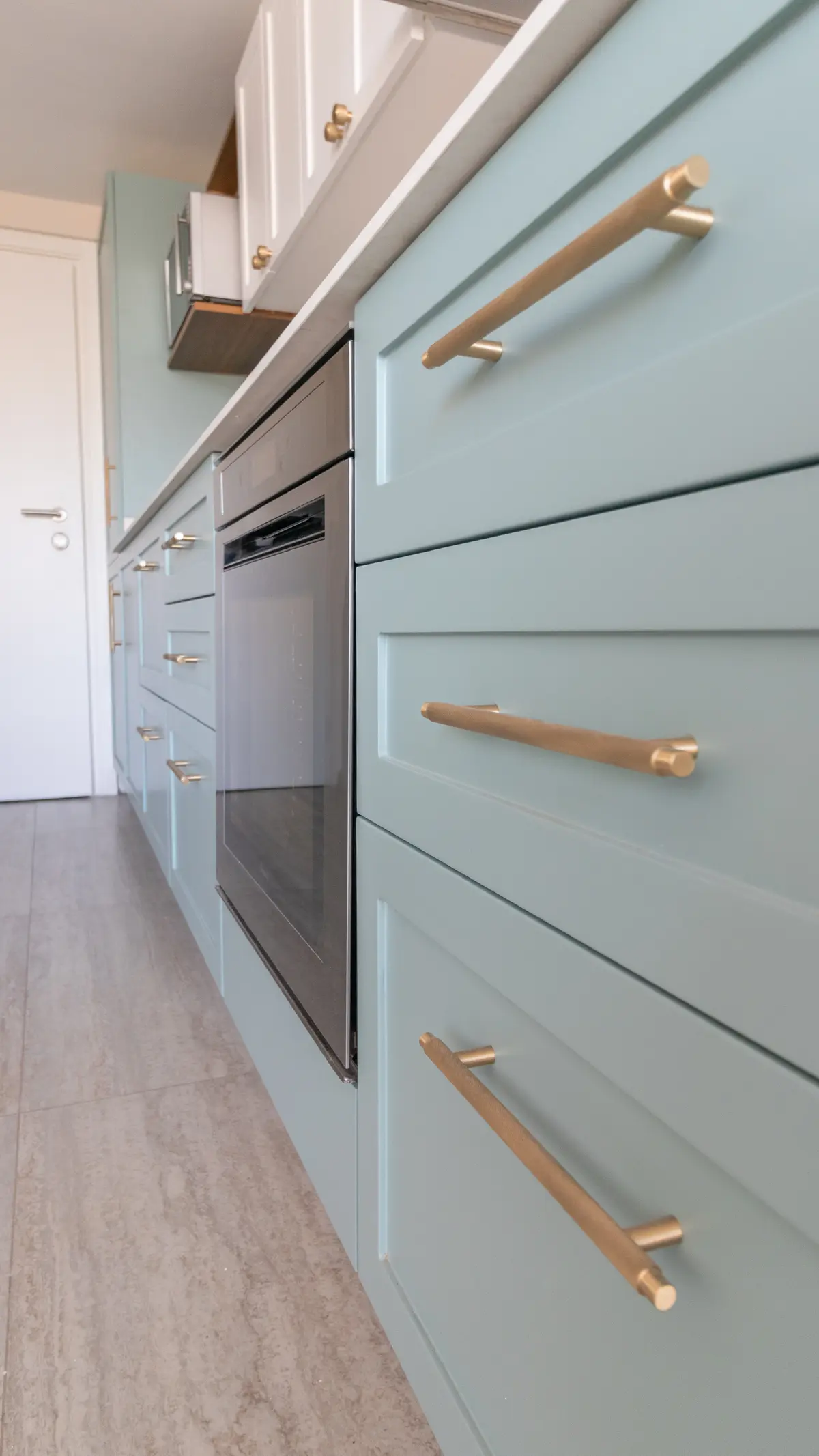 Cocina moderna con gabinetes azul claro y herrajes de latón — proyecto Martinez - Estudio Libria, por ABEJA CONCEPT, en Belgrano