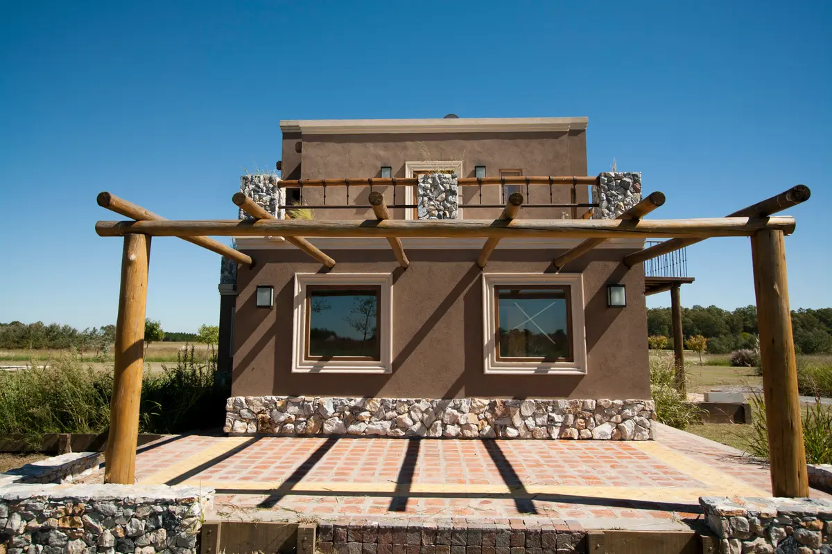 Fachada de casa estilo mediterrâneo com pergolado e pátio — projeto Inmuebles, por Geo Estudio, em Buenos Aires