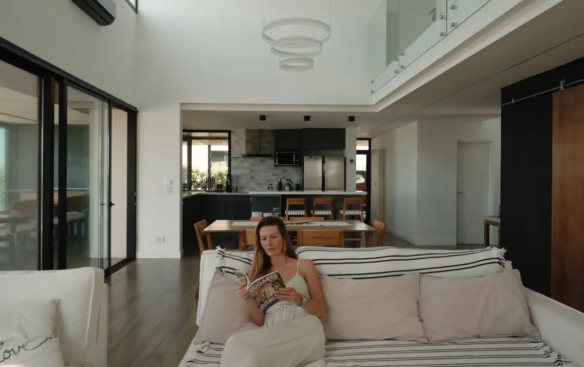 Dormitorio moderno con cama queen y cocina abierta al fondo — proyecto Essence House, por Estudio UFV72, en Pilar