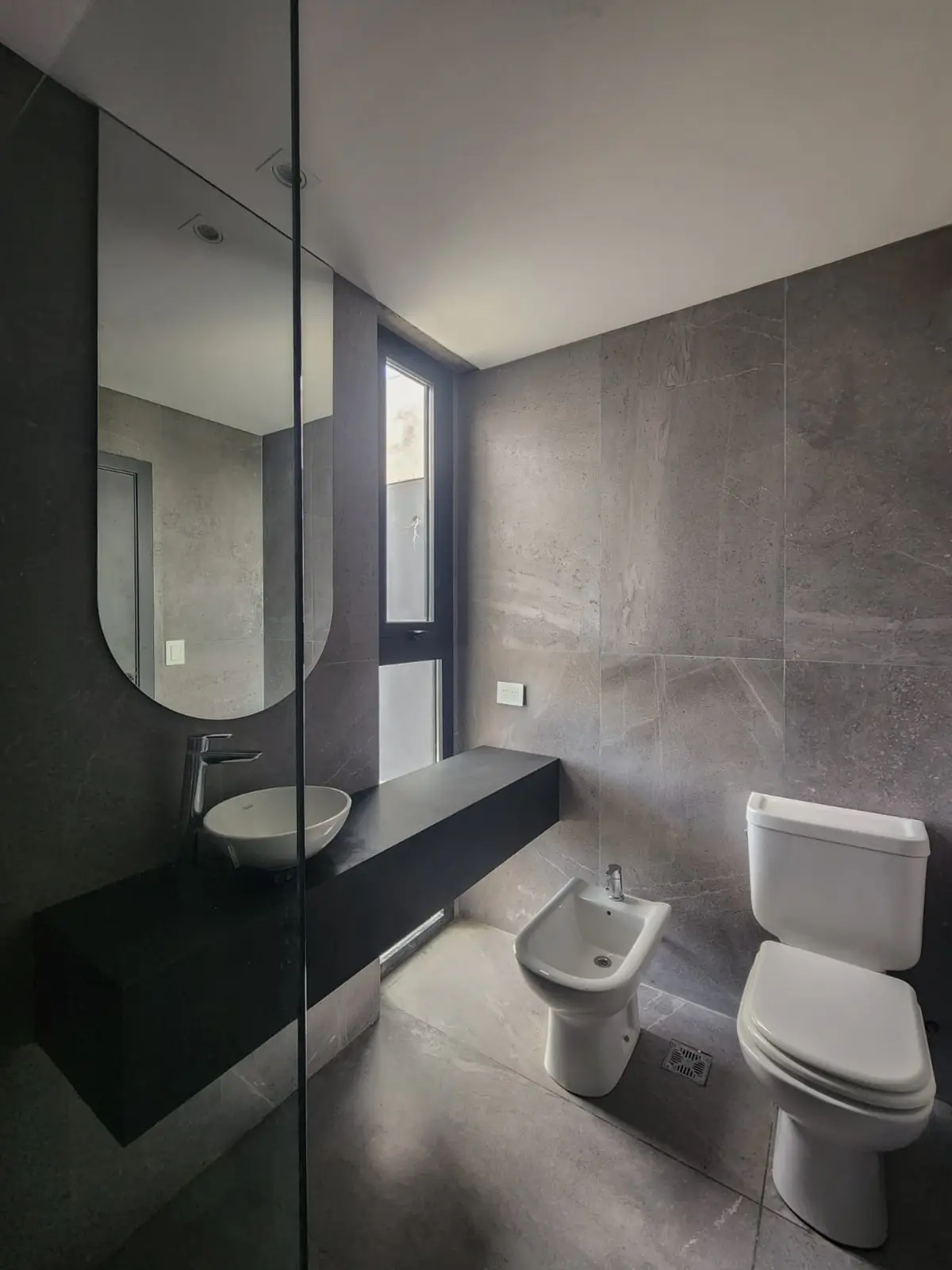 Baño moderno con bidet, inodoro y lavabo sobre mesada flotante — proyecto San Sebastian 318, por BARBALACO ARQUITECTOS, en Pilar