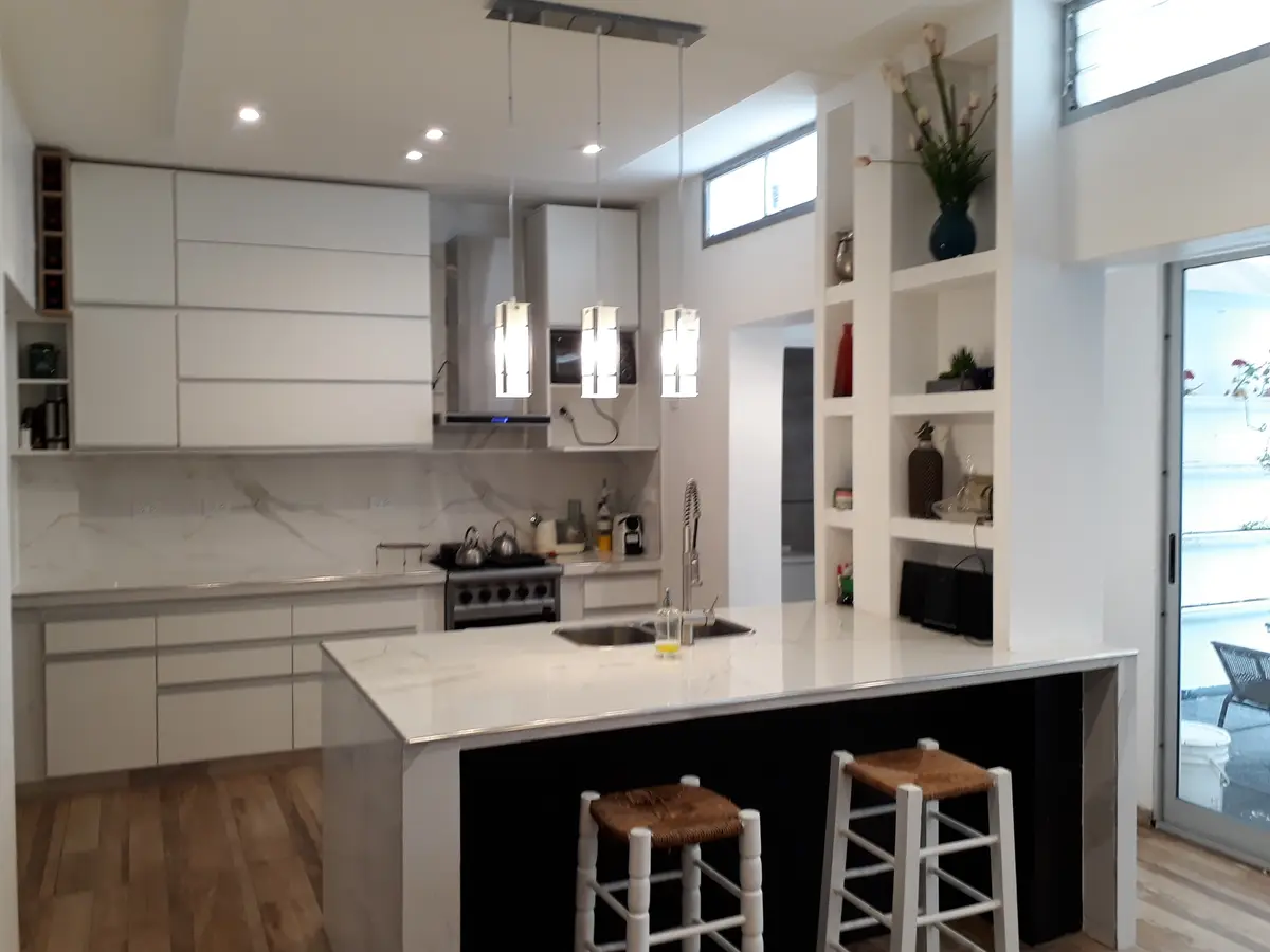Cocina moderna minimalista con isla central y detalles de mármol — proyecto Remodelación cocina 8, por Zima Arquitectura, en La Plata