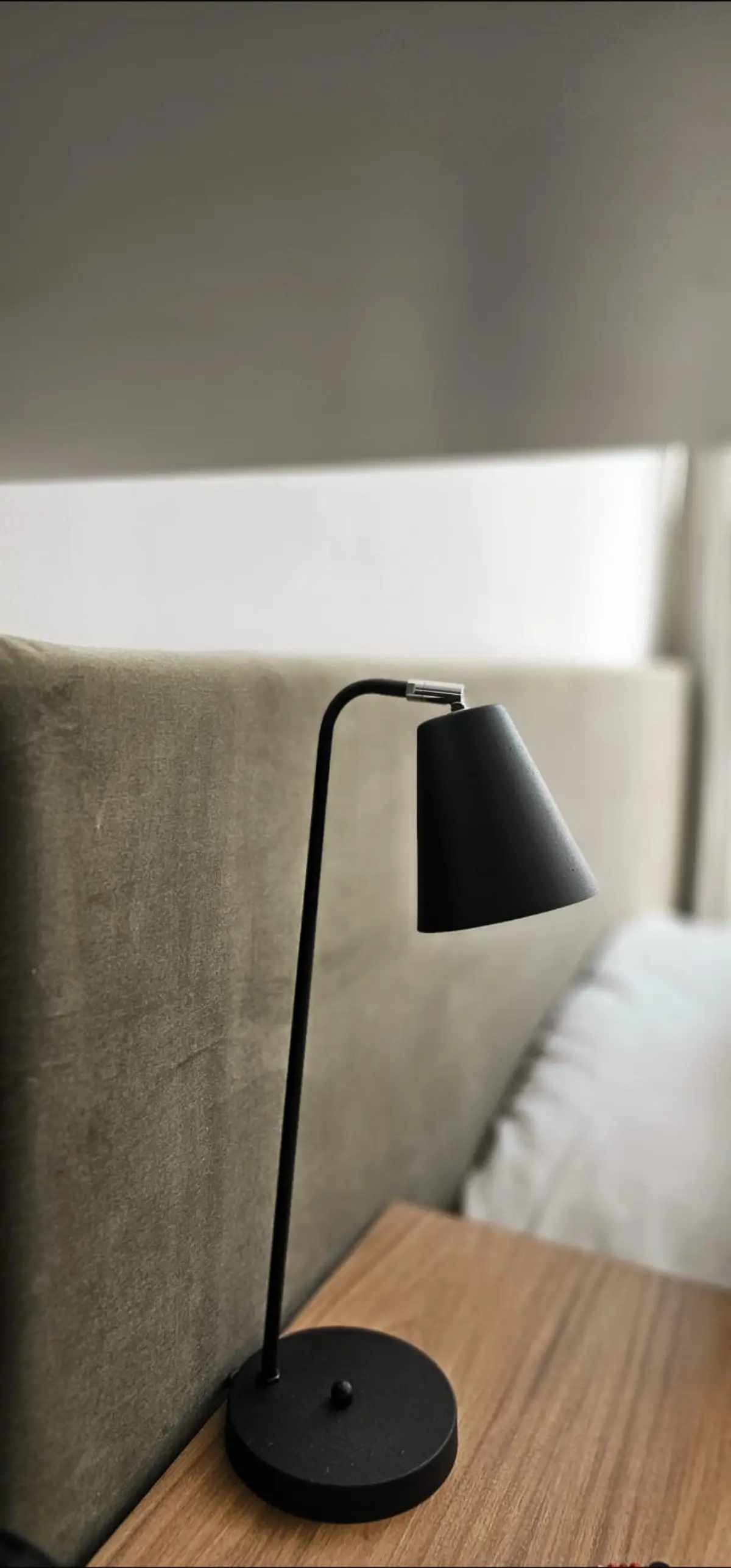 Luminária preta minimalista ao lado de cama em quarto moderno com parede de tecido — projeto Callao, por Claraboia, em Recoleta
