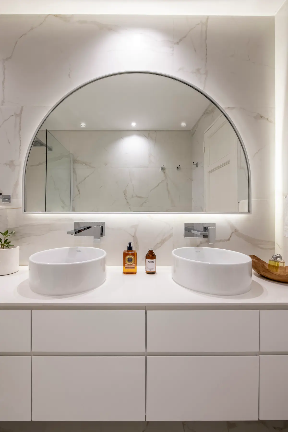 baño moderno con doble lavabo y espejo arqueado — proyecto AS, por Estudio Basa, en Buenos Aires
