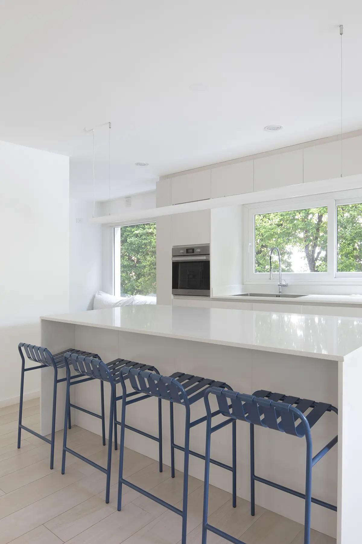 Cozinha moderna com ilha, bancos azuis e grandes janelas — projeto Reforma Isla del Sol, por Estudio YME, em Rincón de Milberg