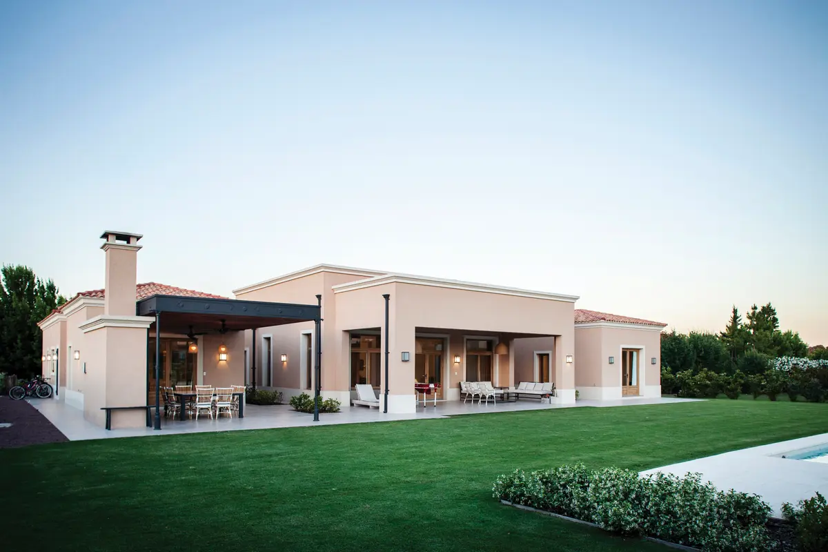 Fachada de casa moderna estilo mediterrâneo com pérgula e pátio — projeto Casa en Pilará, por Mazzinghi Sanchez