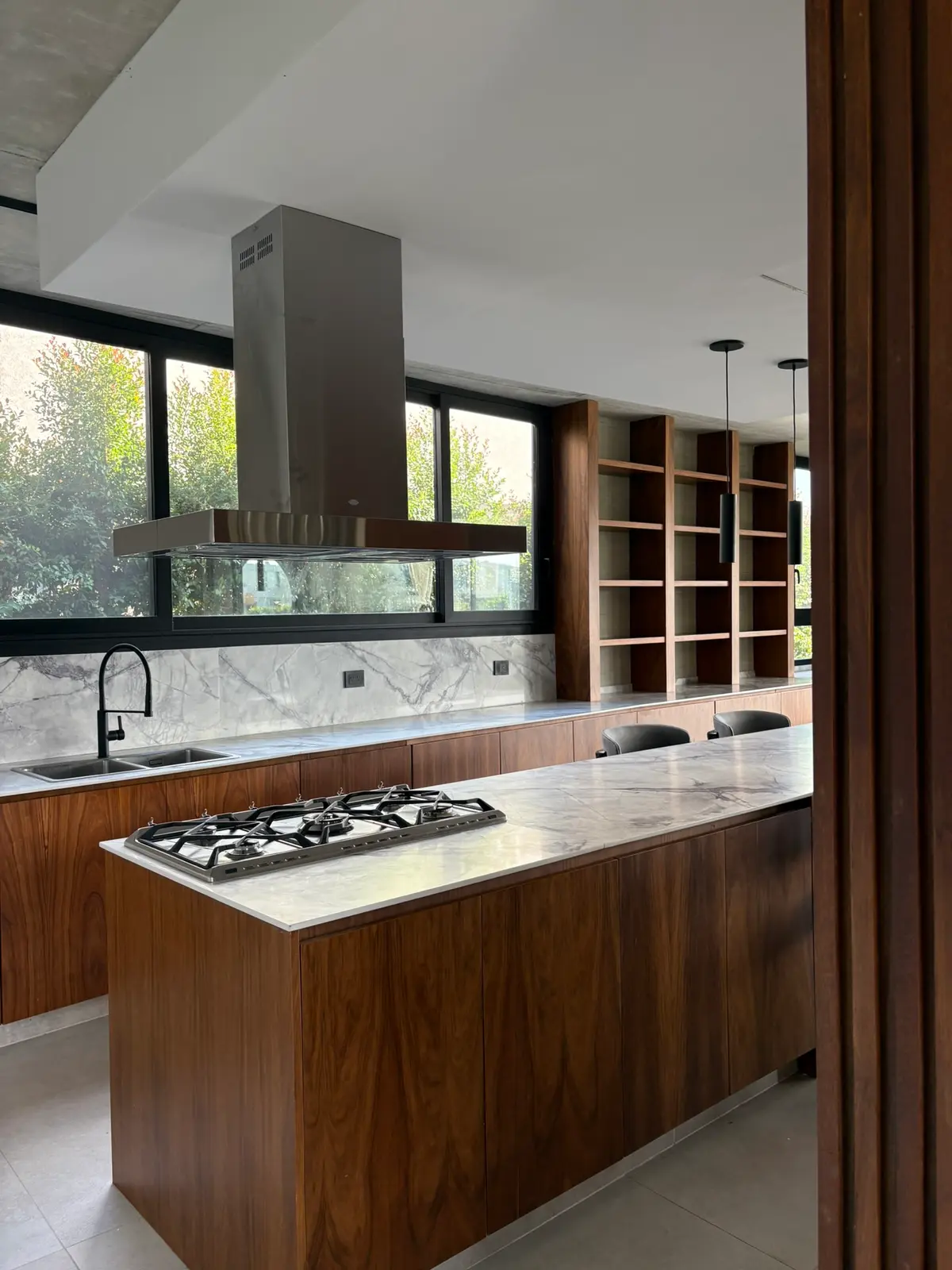 Cocina moderna con isla, madera oscura y mármol — proyecto Carpinchos - Estudio Gambotto, por ABEJA CONCEPT, en Nordelta