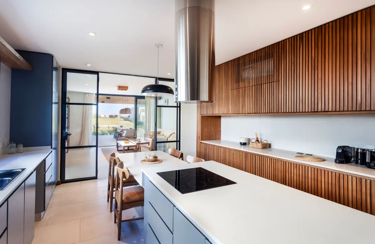 Cozinha moderna conceito aberto com ilha e parede de ripas de madeira — projeto Casa Tom, por LSA., em Belén de Escobar