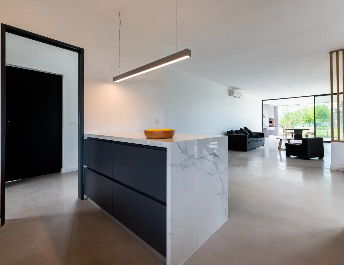 Cocina y living modernos con isla de mármol y hormigón pulido — proyecto Santa Isabel - Andrea Gonzalez, por ABEJA CONCEPT, en Nordelta