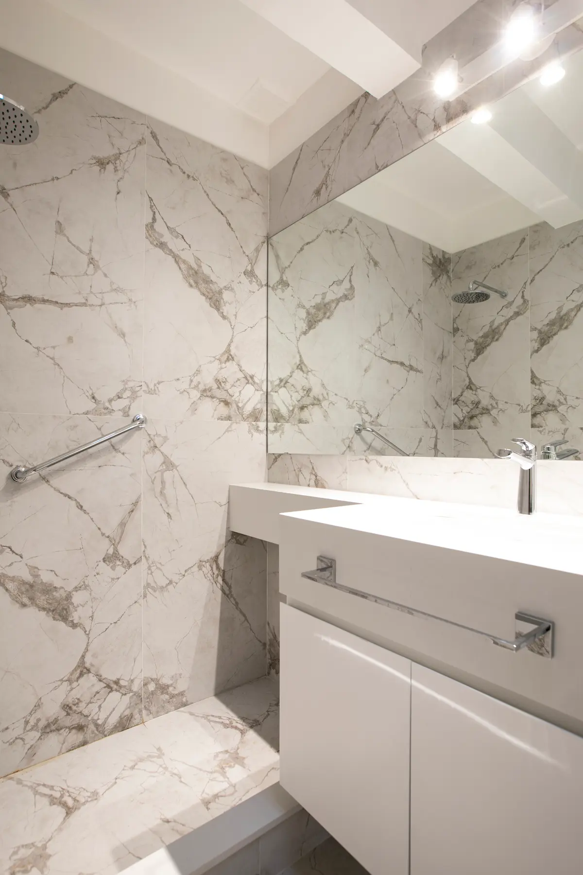 Baño moderno con mármol, mueble flotante y grifería minimalista — proyecto Obra Martinez A, por Arq. Lourdes Yarade Saravia, en Martínez