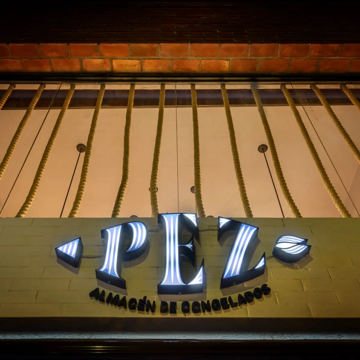 Fachada de local comercial con letrero luminoso azul tipo neon — proyecto PEZ, Almacén de Congelados - Arquitectura Comercial, por Síncresis Arquitectos, en Ciudad de Córdoba