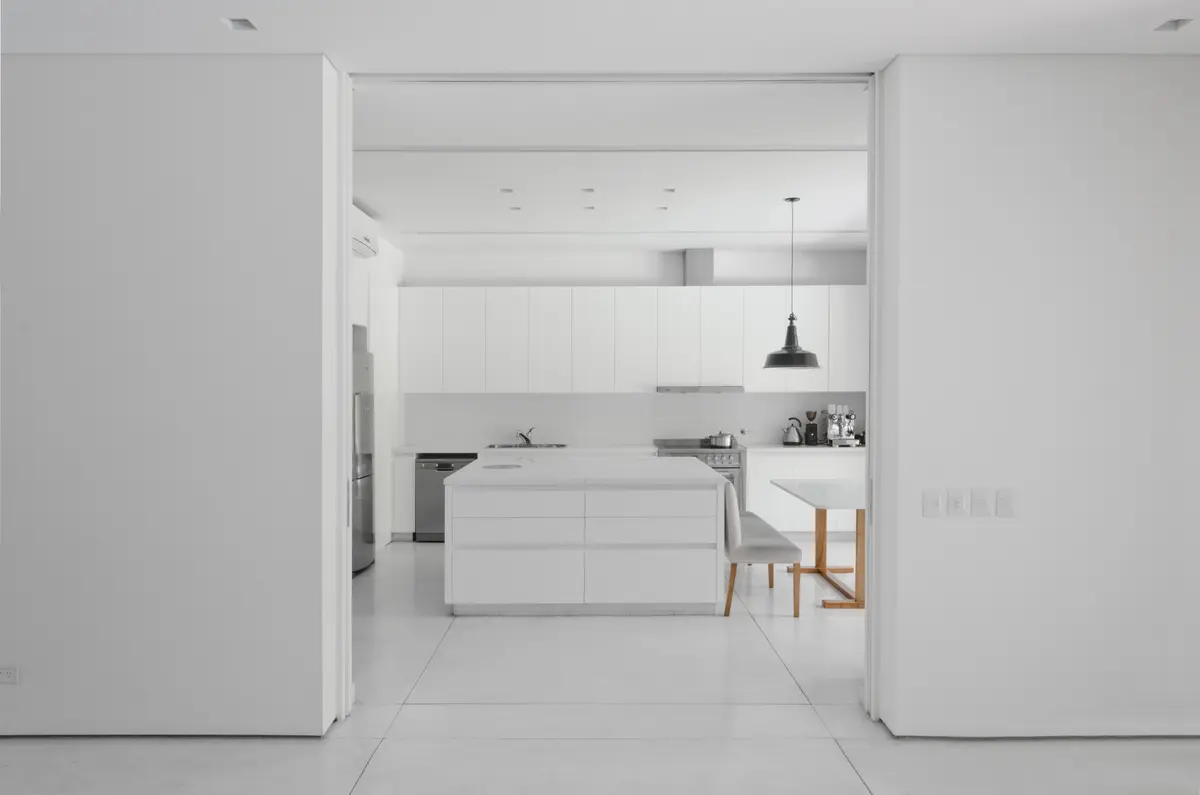 Cocina moderna minimalista blanca con isla y mesa — proyecto Casa D, por Estudio Dado, en Belgrano