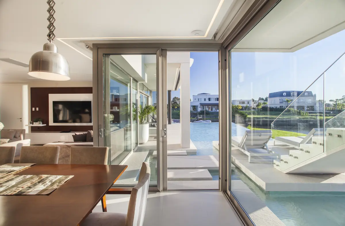 Sala de estar e jantar moderna com vista para piscina e mar — projeto Casa Caledoiscopio, por Apaarquitectura, em Nordelta