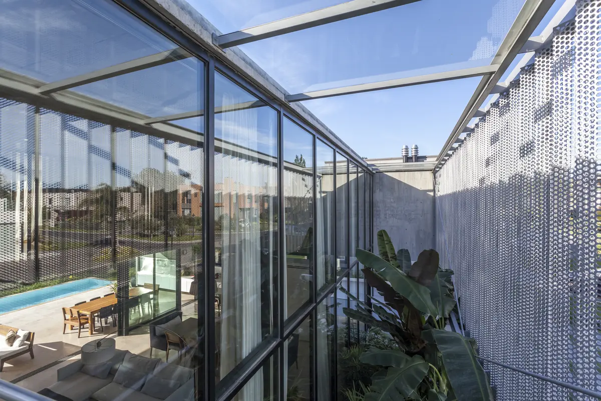 Terraza moderna con paredes de vidrio y pantalla metálica — proyecto Casa ADR, por Jorgelina Tortorici & asoc., en B1846 Adrogué