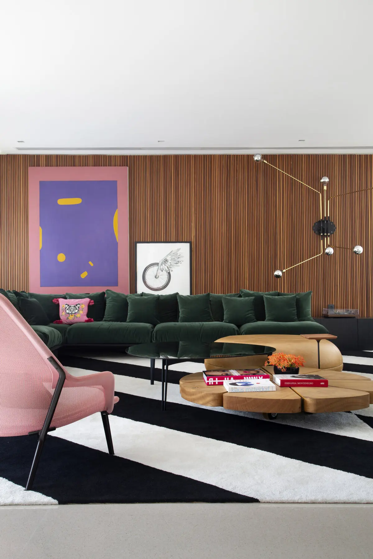 Living moderno con sofá verde oscuro y sillón rosa sobre tapete geométrico — proyecto BM House, por Studio Ro-ca