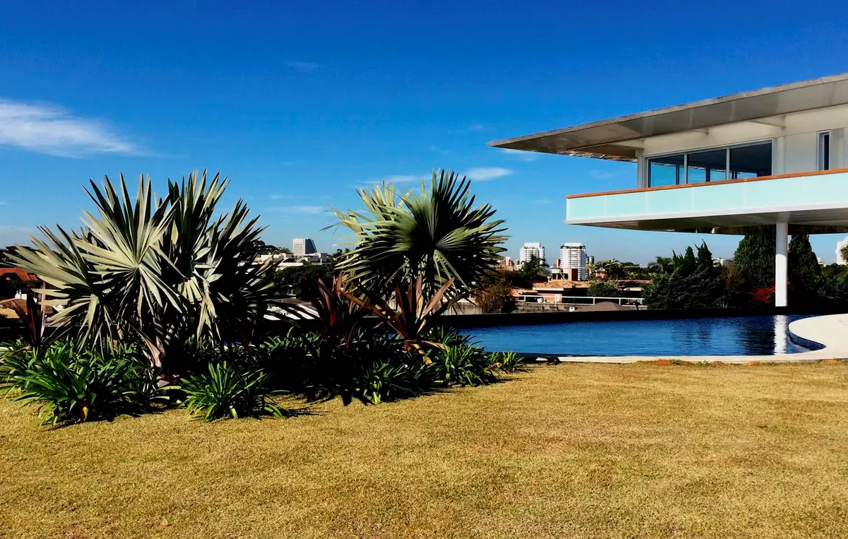 Casa moderna con pileta, jardín con palmeras y arquitectura contemporánea — proyecto Residência HC, por Gil Fialho