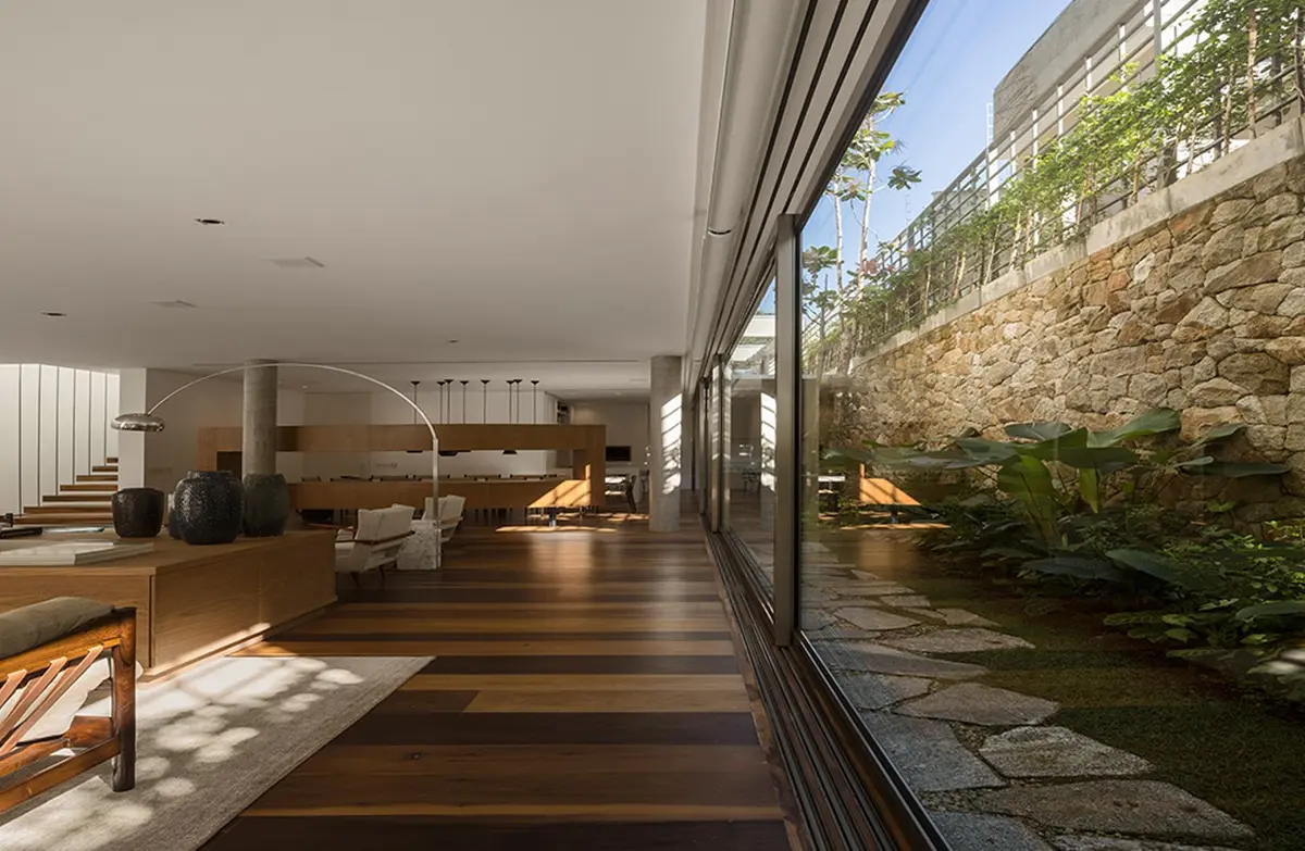 Living moderno con piso de madera, ventanal integrado y jardin exterior — proyecto Residência AC, por Gil Fialho