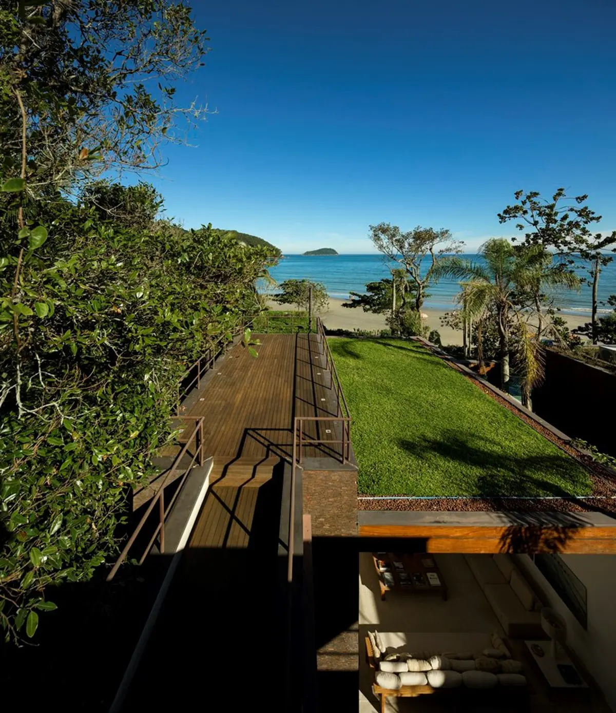 Terraza con deck, jardín y vista al mar cristalino — proyecto West Whales, por Gil Fialho