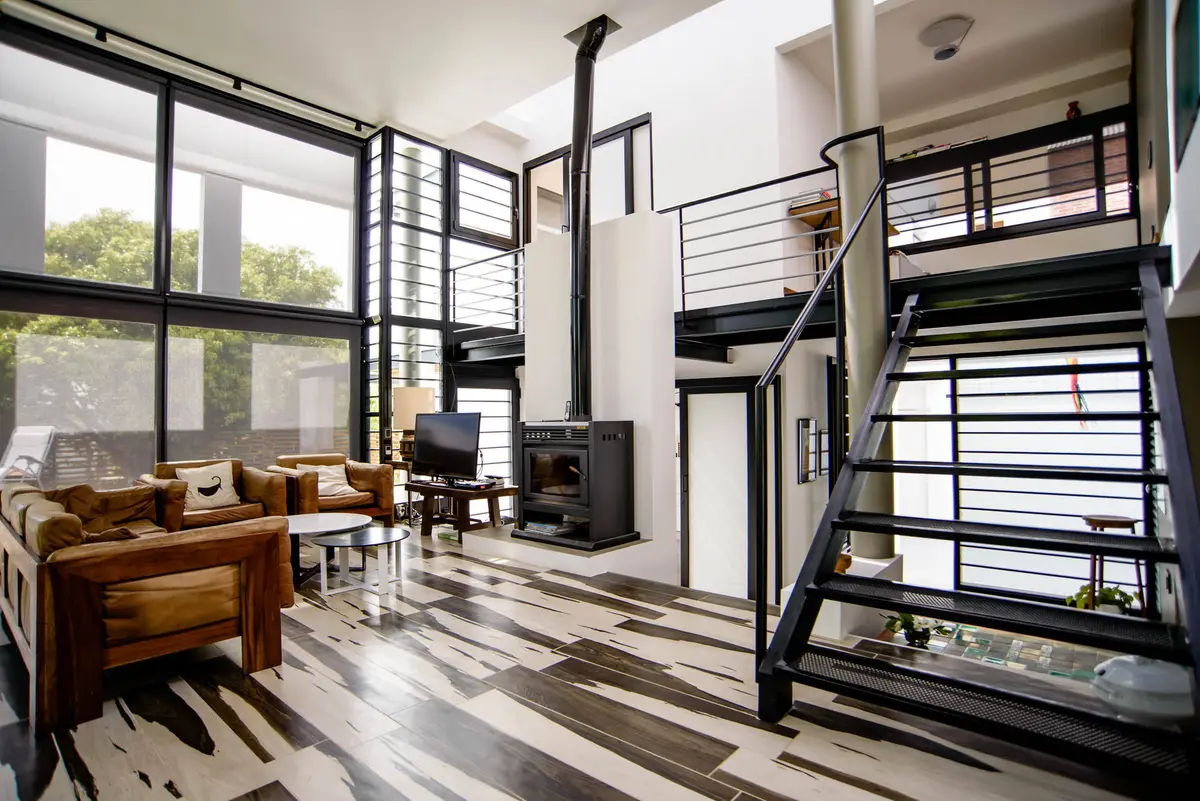 Sala de estar moderna com pé-direito duplo e escada industrial — projeto CASA GONNET, por LEONE LORAY ARQUITECTOS, em Gonnet