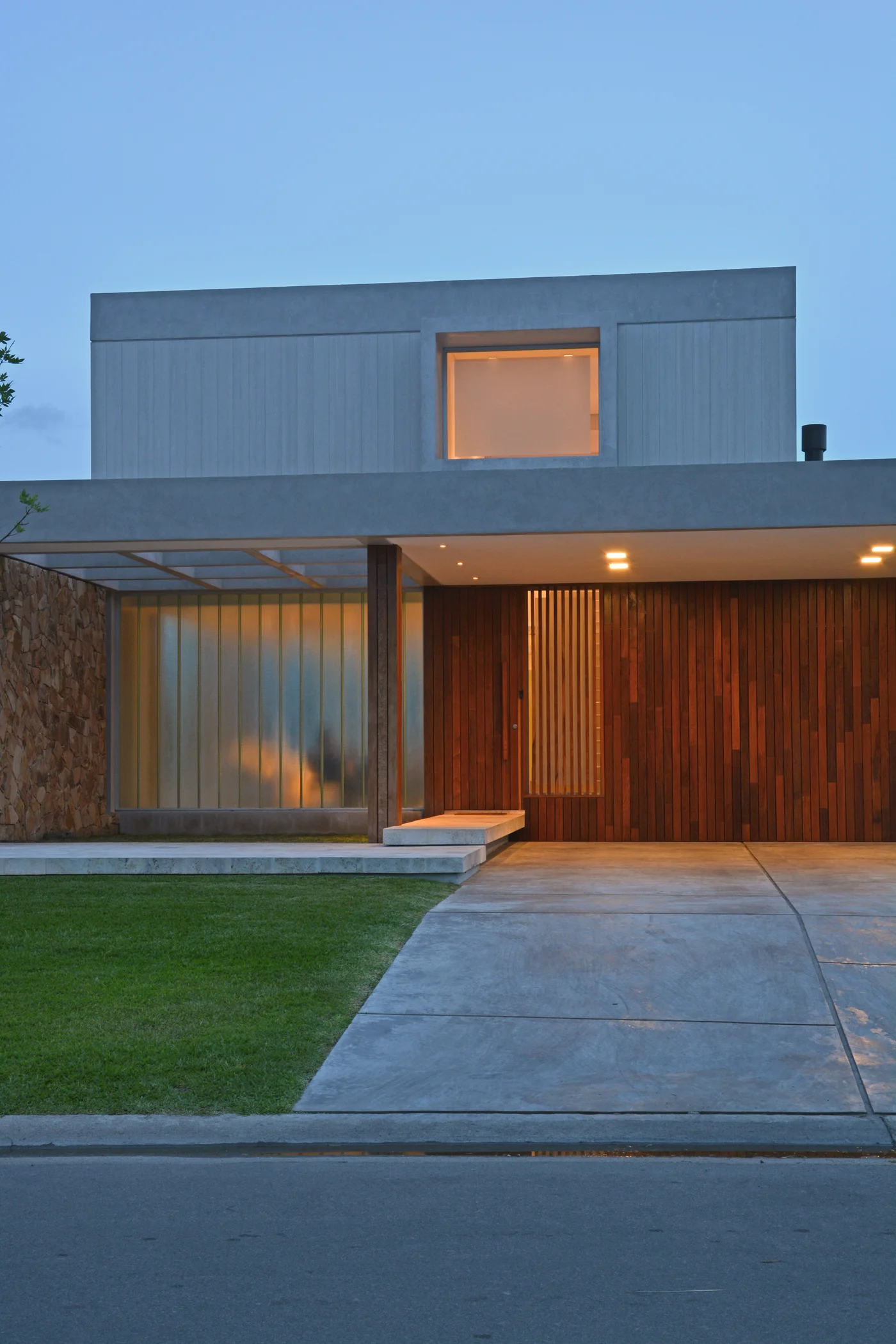 Fachada moderna con revestimientos de madera, hormigón y piedra.