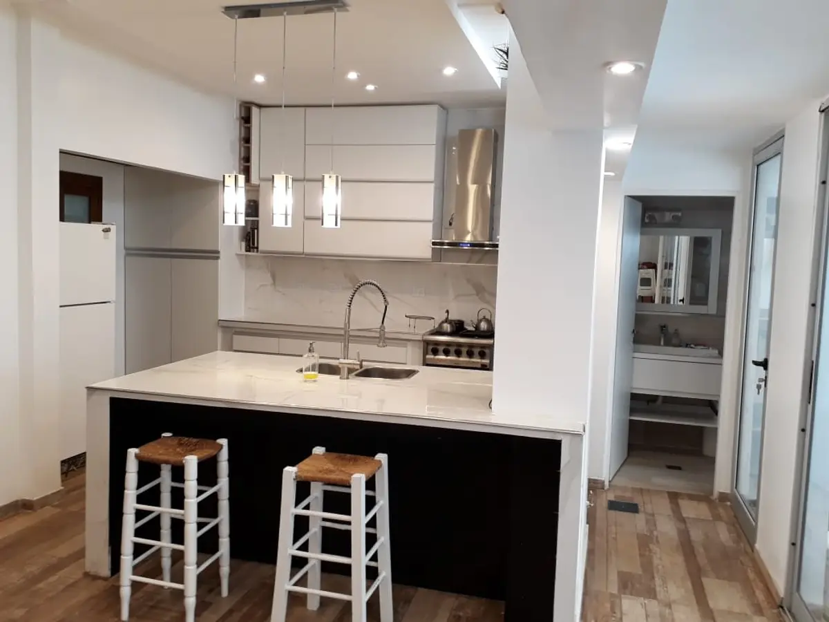 Cocina y comedor modernos con isla central y luces colgantes — proyecto Remodelación cocina 8, por Zima Arquitectura, en La Plata
