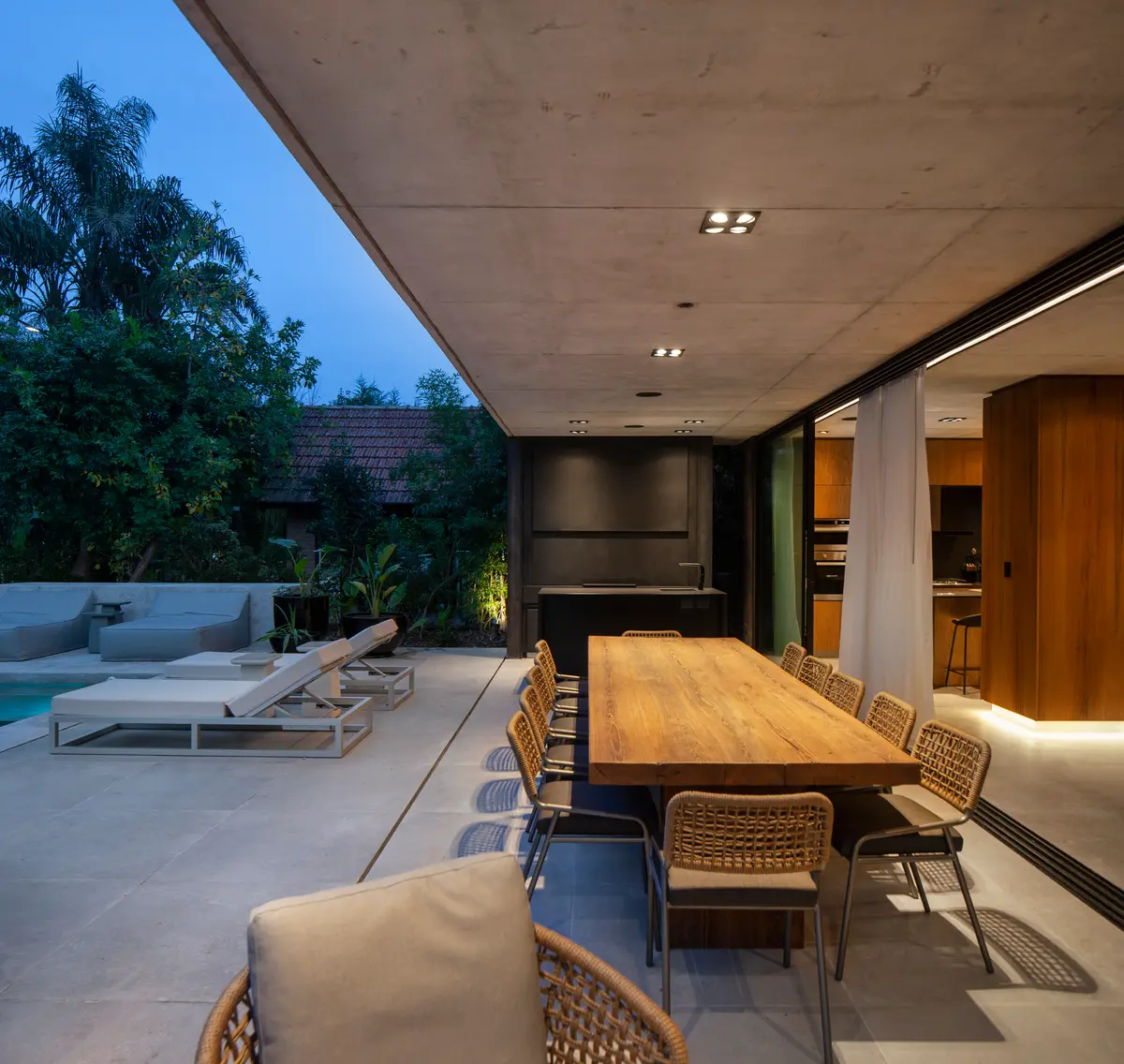 Sala de jantar moderna semi-externa com mesa de madeira e jardim — projeto CASA AH, por GMARQ, em Garin