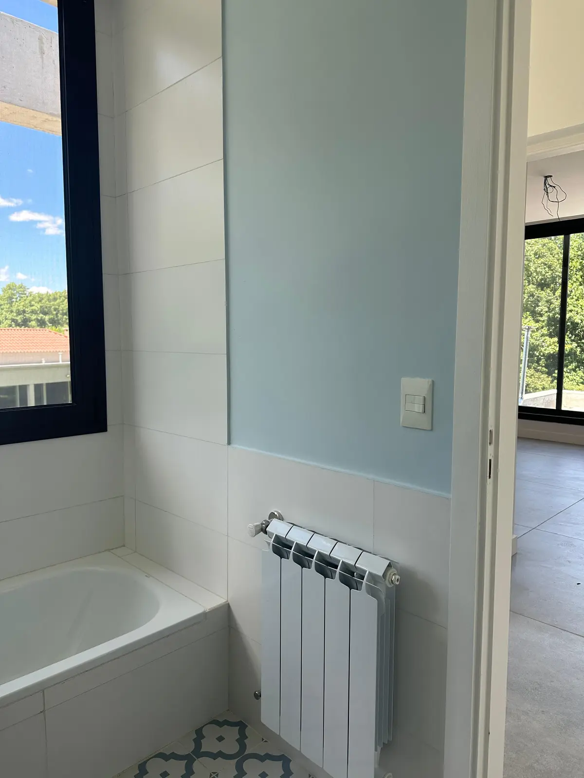 Baño minimalista con pared celeste, radiador y ventana con vistas — proyecto Radiadores - Golf Club Argentino , por Climatizacion HD, en Pilar
