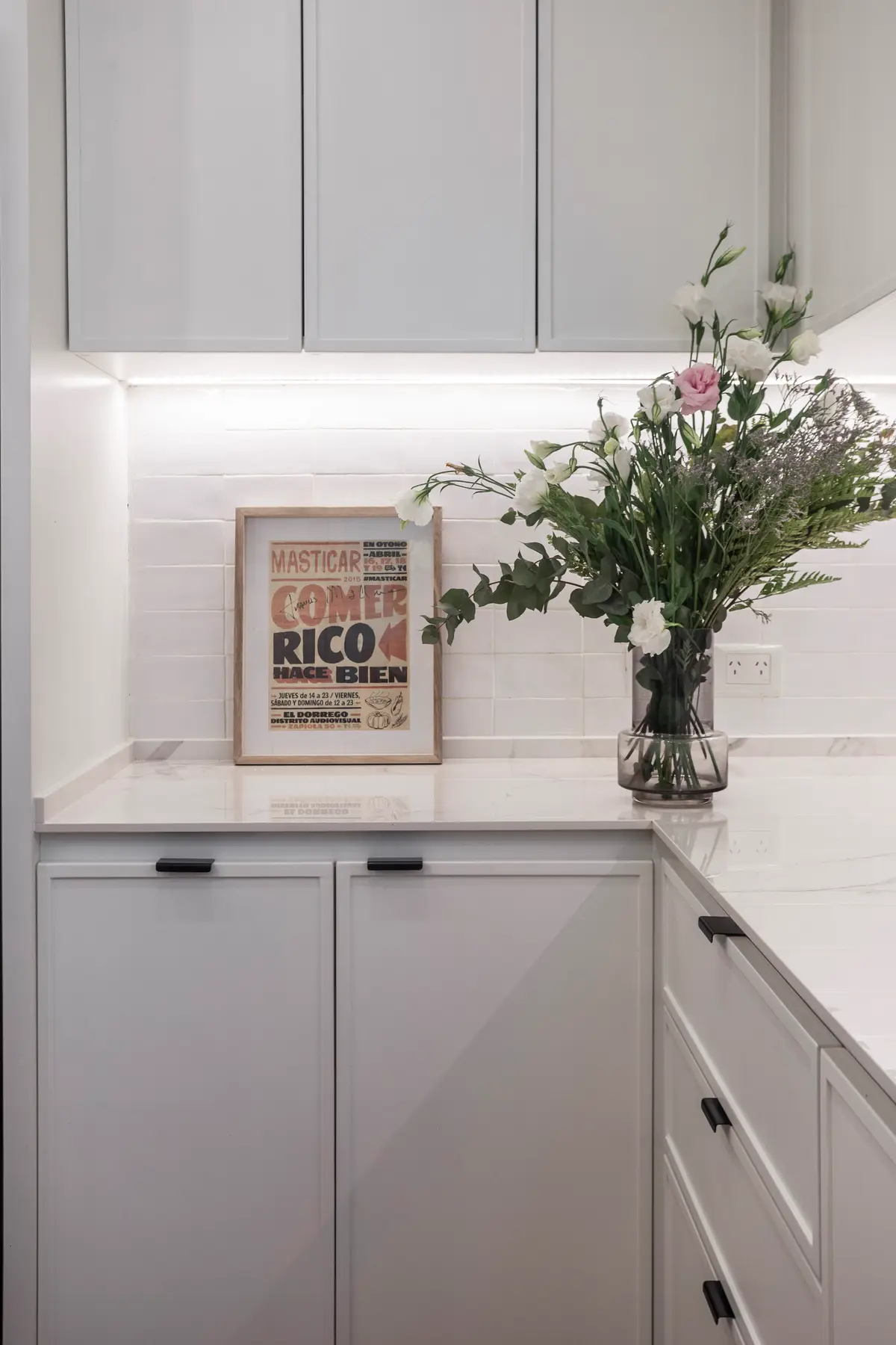 Cozinha moderna com armários brancos, mármore e flores — projeto Bustamante, por JT ARQUITECTURA, em Buenos Aires