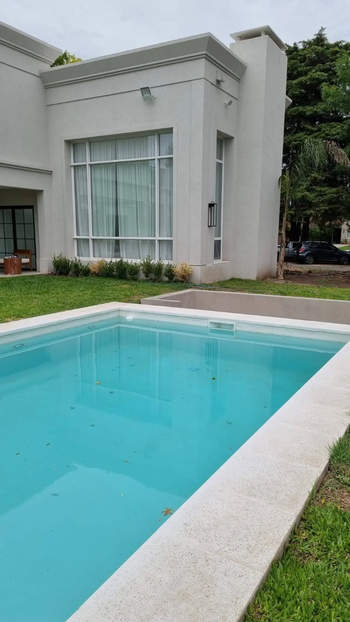 Casa moderna con piscina azul y fachada de concreto blanco — proyecto Casa estilo clásico moderno, por Vidal Bianchi arquitectura, en Pilar