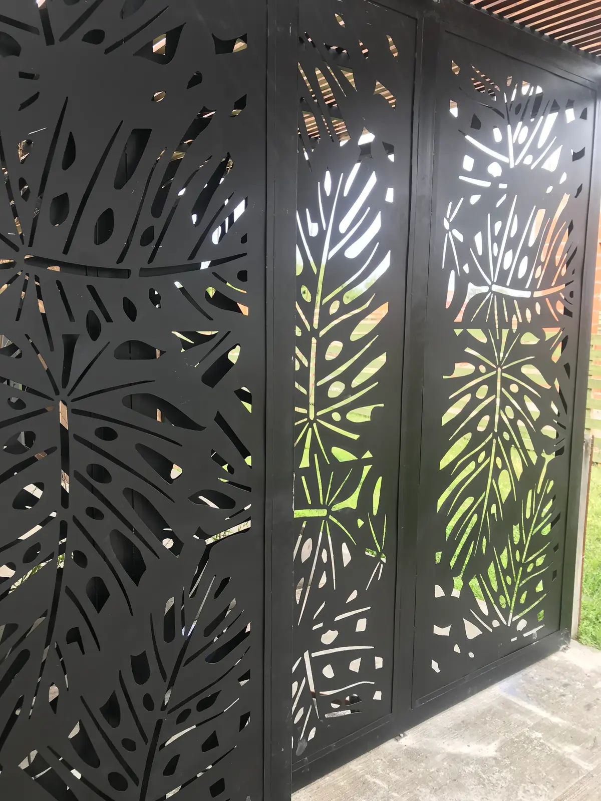 fachada moderna com painéis metálicos pretos com recortes de folhas — projeto Chapa calada decorativa, tríptico árbol de la vida oara portones corredizos y ce, por Pintastic, em Be