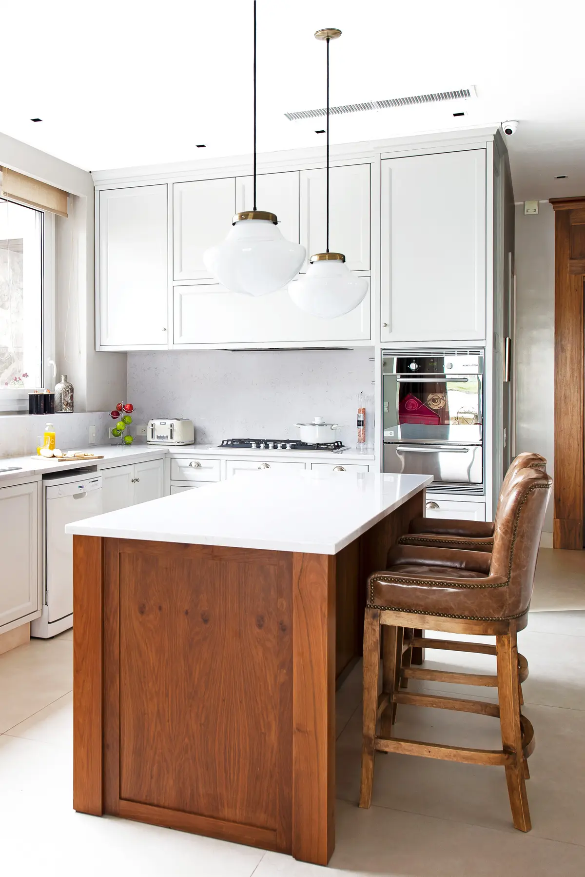 Cocina moderna con isla de madera, bancos vintage y luces colgantes — proyecto Casa MF, por Estudio Junor, en Belén de Escobar