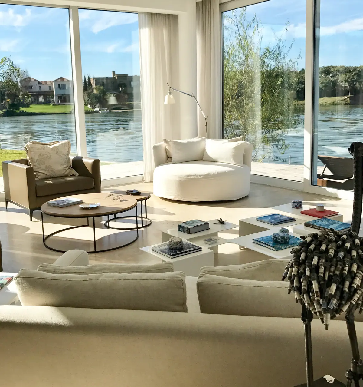 Living moderno con vista al lago y sofá curvo grande — proyecto CASA LAGUNA, por Estudio Xime Fontan Balestra, en Tigre