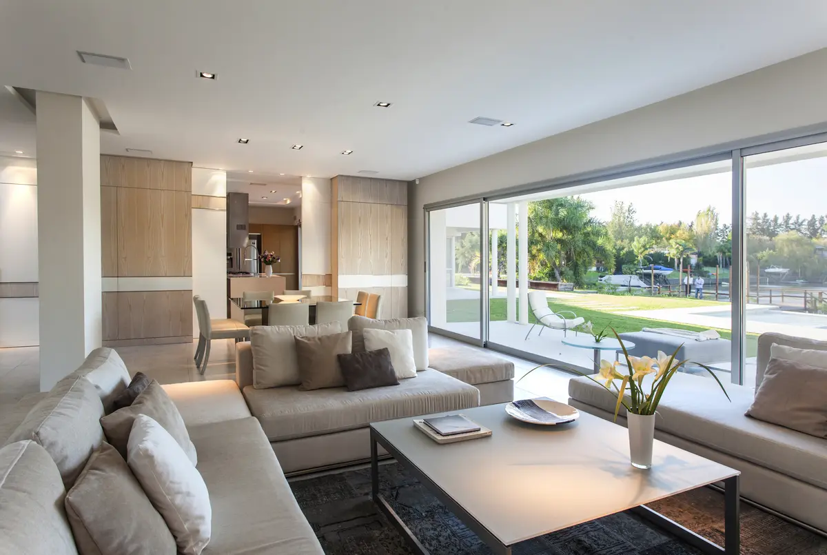 Living comedor moderno con ventanales y jardín exterior — proyecto Modernismo Náutico, por Apaarquitectura, en Tigre