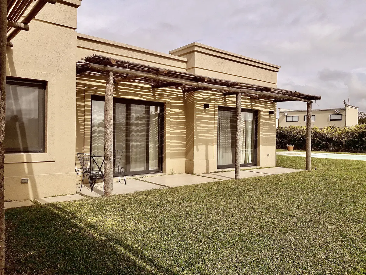 Fachada moderna com pérgola de madeira e grandes janelas frente ao jardim — projeto Santa Teresa Villanueva 2, por Marconi Silva Arquitectos, em Benavidez