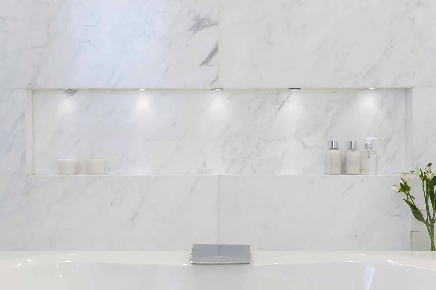 Baño moderno con paredes de mármol y bañera exenta.
