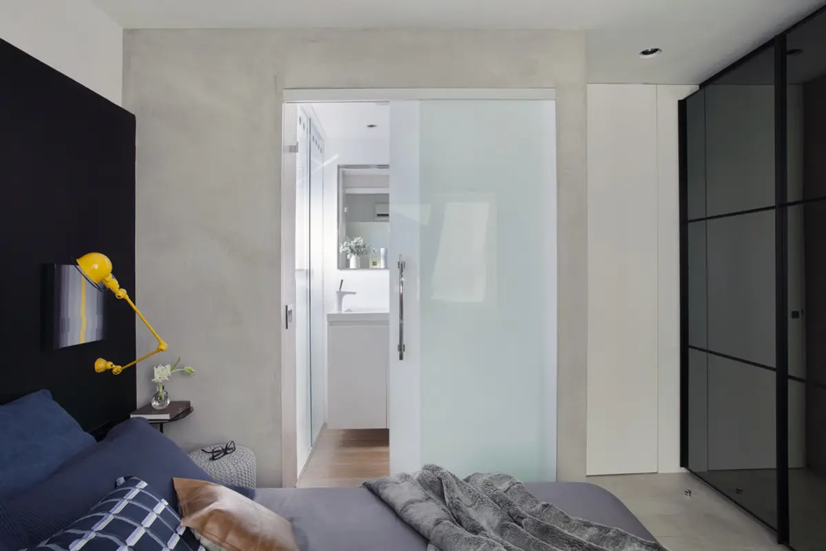 dormitorio moderno con cama gris y acceso a baño mediante puerta blanca — proyecto RF House, por Studio Ro-ca