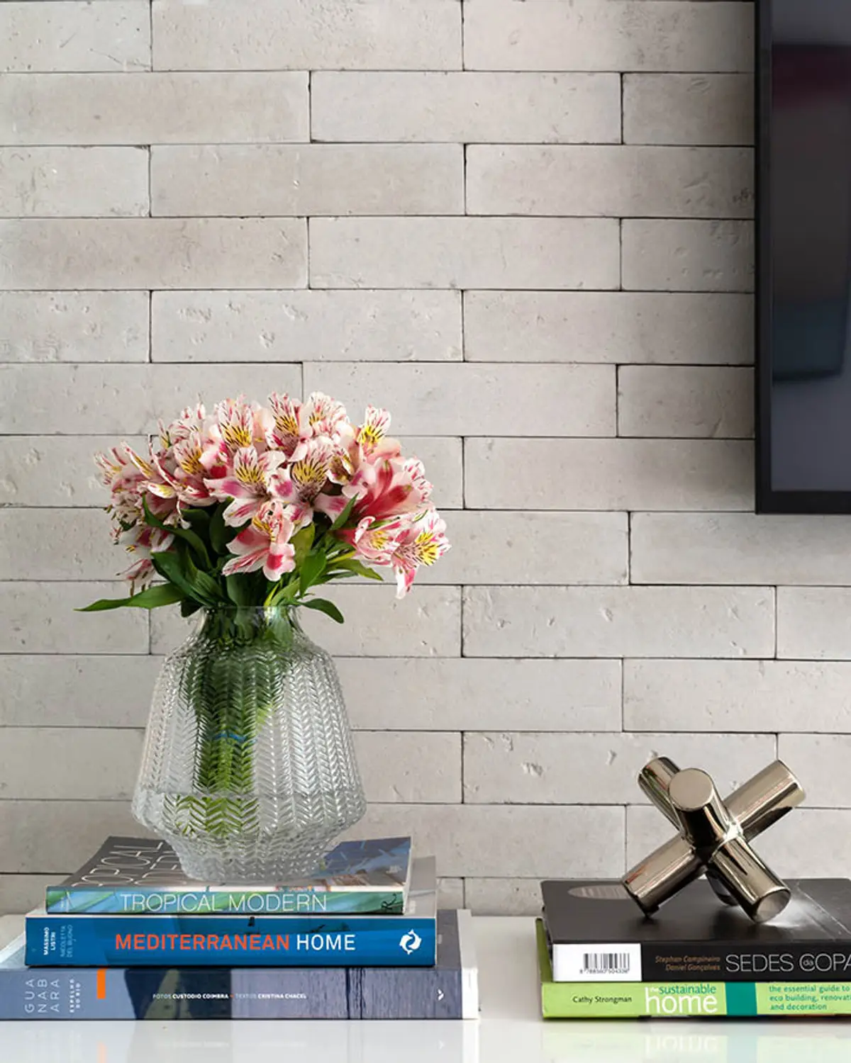Pared de ladrillo blanco con florero y libros de arquitectura sobre mesada — proyecto Apartamento Nóbrega, por Amanda Miranda