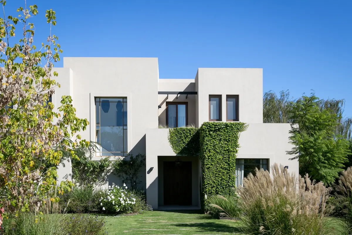 Fachada moderna branca com parede verde e deck de madeira — projeto Pilara I, por Escalante Vela Arquitectos, em Pilará