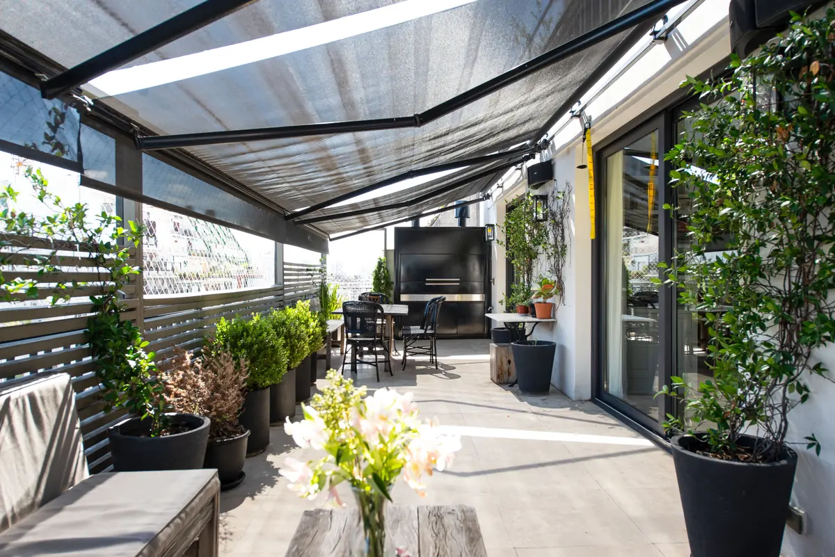 Varanda moderna com pérgola retrátil e plantas em terraço urbano — projeto Quintana, por Escalante Vela Arquitectos, em CABA