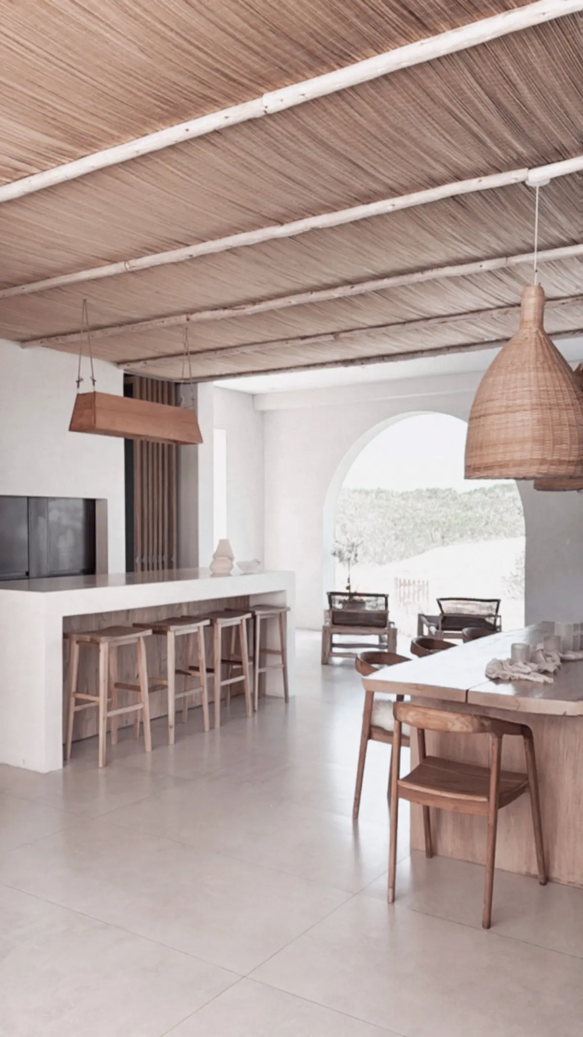 Cozinha moderna mediterrânea com ilha de concreto e teto de palha — projeto El Refugio, por Grupo Pauta Arquitectura, em Pinamar