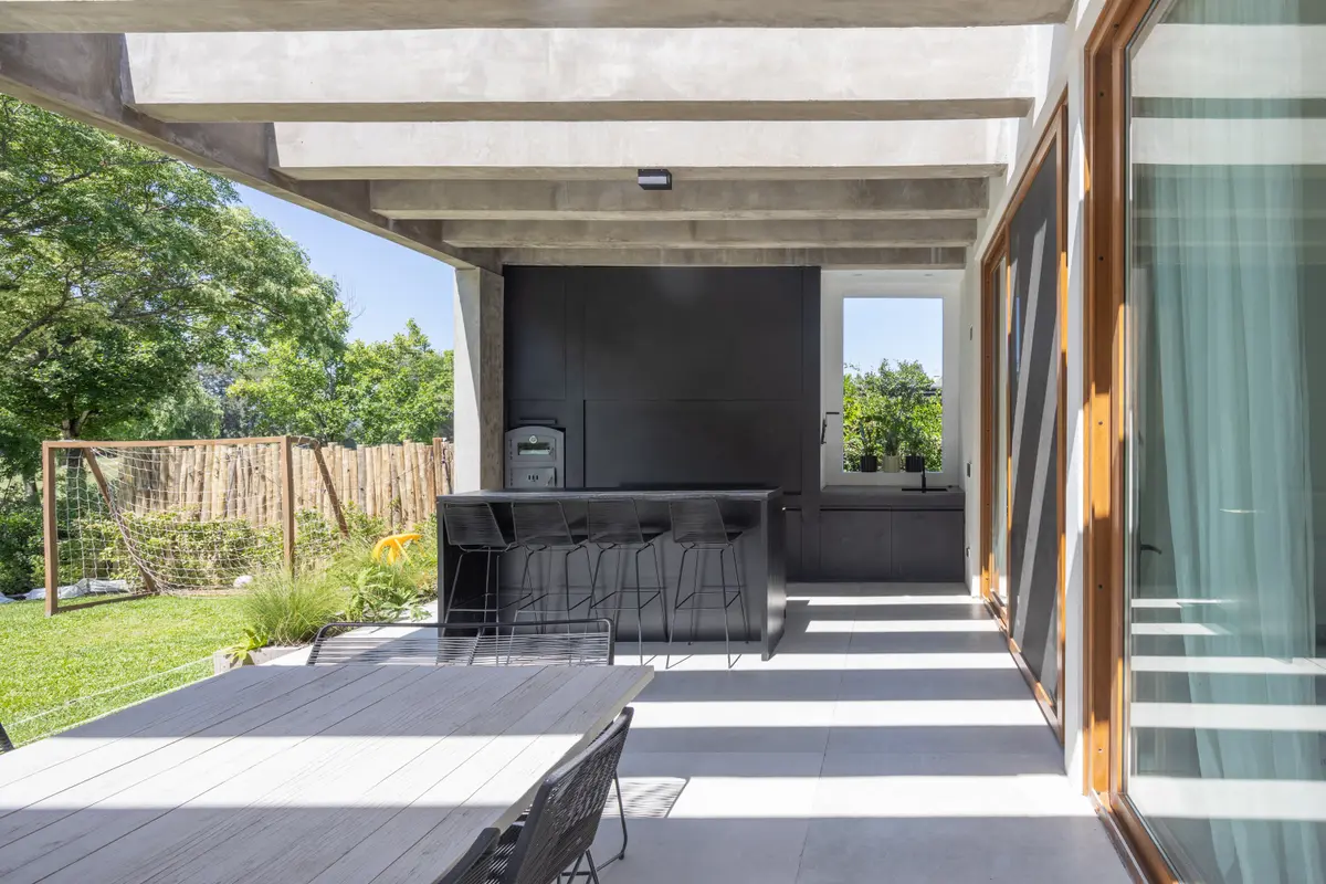 Área de pátio moderna com pérgola de concreto e cozinha externa — projeto CASA BaCa, por Alfredo Orfila arquitectura, em Benavidez