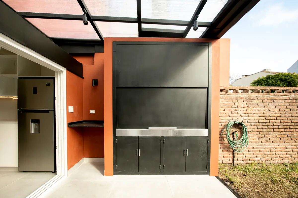 área de churrasqueira moderna semi-externa com tijolos e detalhes em metal preto — projeto Obra Martinez A, por Arq. Lourdes Yarade Saravia, em Martínez