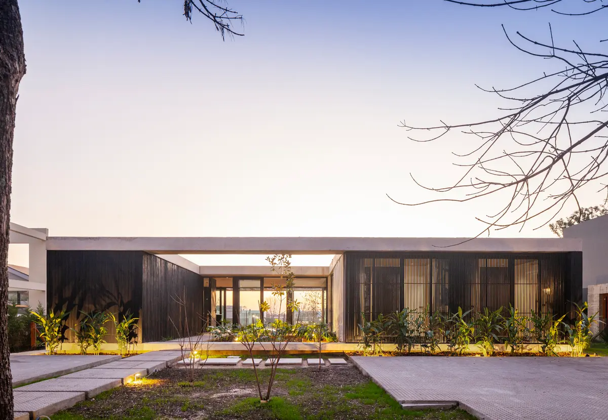 fachada moderna minimalista com jardim e luzes quentes — projeto Casa ROMA, por V2 Arquitectos, em City Bell