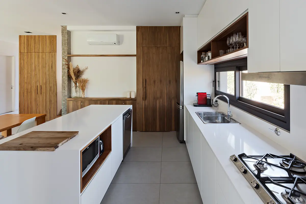 Cozinha moderna com ilha de cascata e armários de madeira — projeto CASA RDV, por Rastro Estudio, em San Isidro