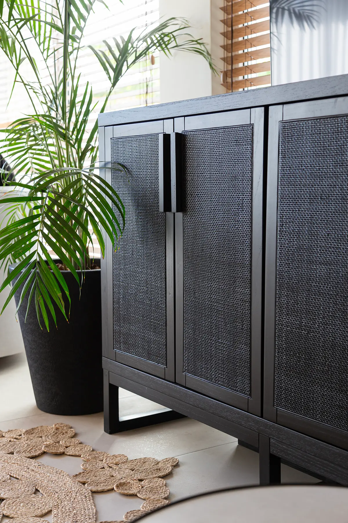 mueble de rattan oscuro con palmera y alfombra floral — proyecto Proyecto Gaby P. , por LINEA NETA diseño interior , en Canning