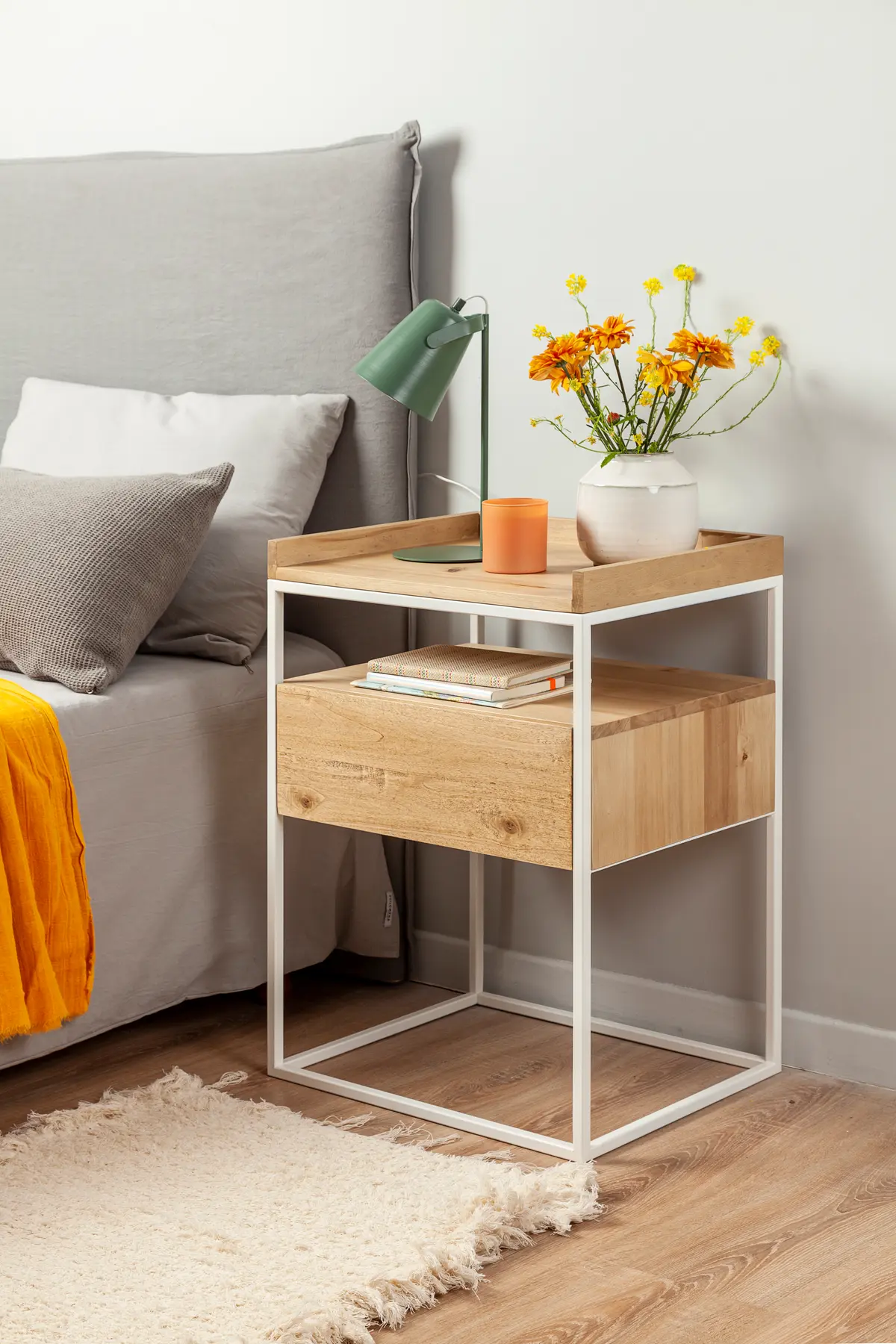 Mesita de noche de madera y metal con cama gris y flores amarillas — proyecto Mesas de luz, por ALTORANCHO, en San Isidro
