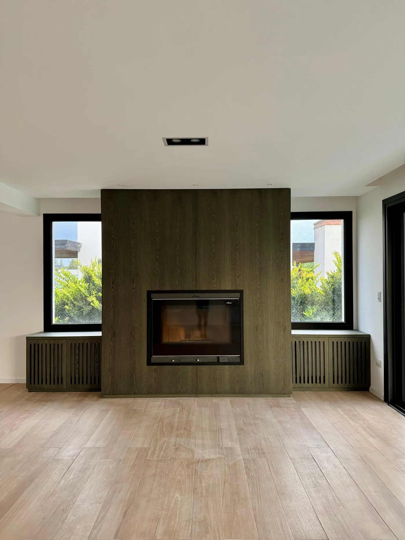 Living moderno con chimenea de madera y grandes ventanales