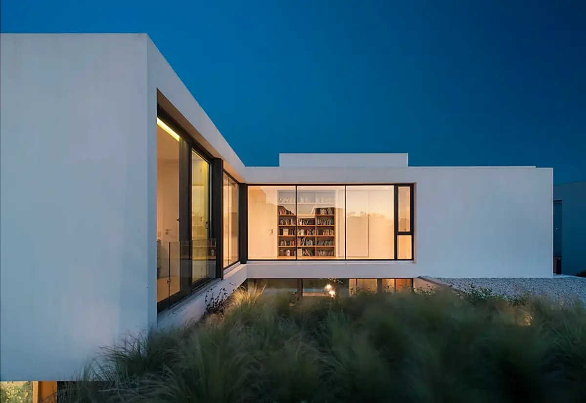 Casa moderna branca com grandes janelas e vegetação exuberante — projeto Casa Lombardi, por Estudio Ramos
