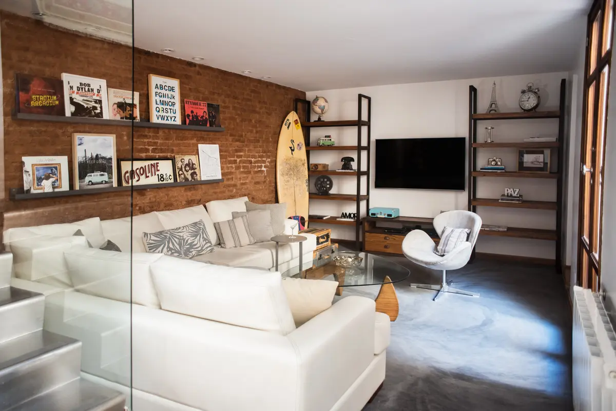 Sala de estar industrial com tijolo aparente e sofá branco modular — projeto Defensa, por Estudio Basa, em CABA