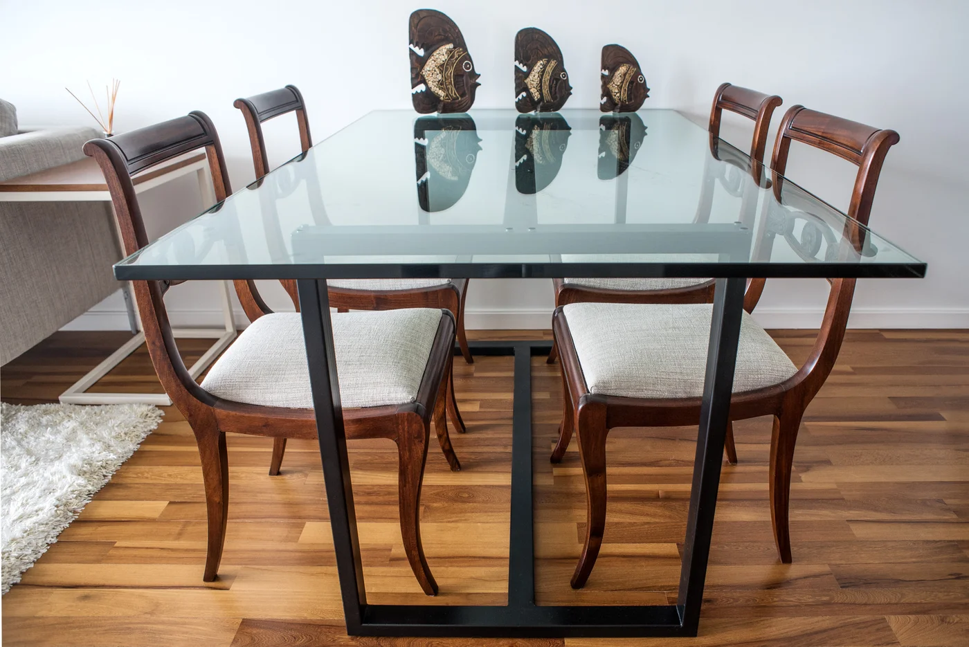 Comedor moderno con mesa de vidrio y seis sillas de madera.